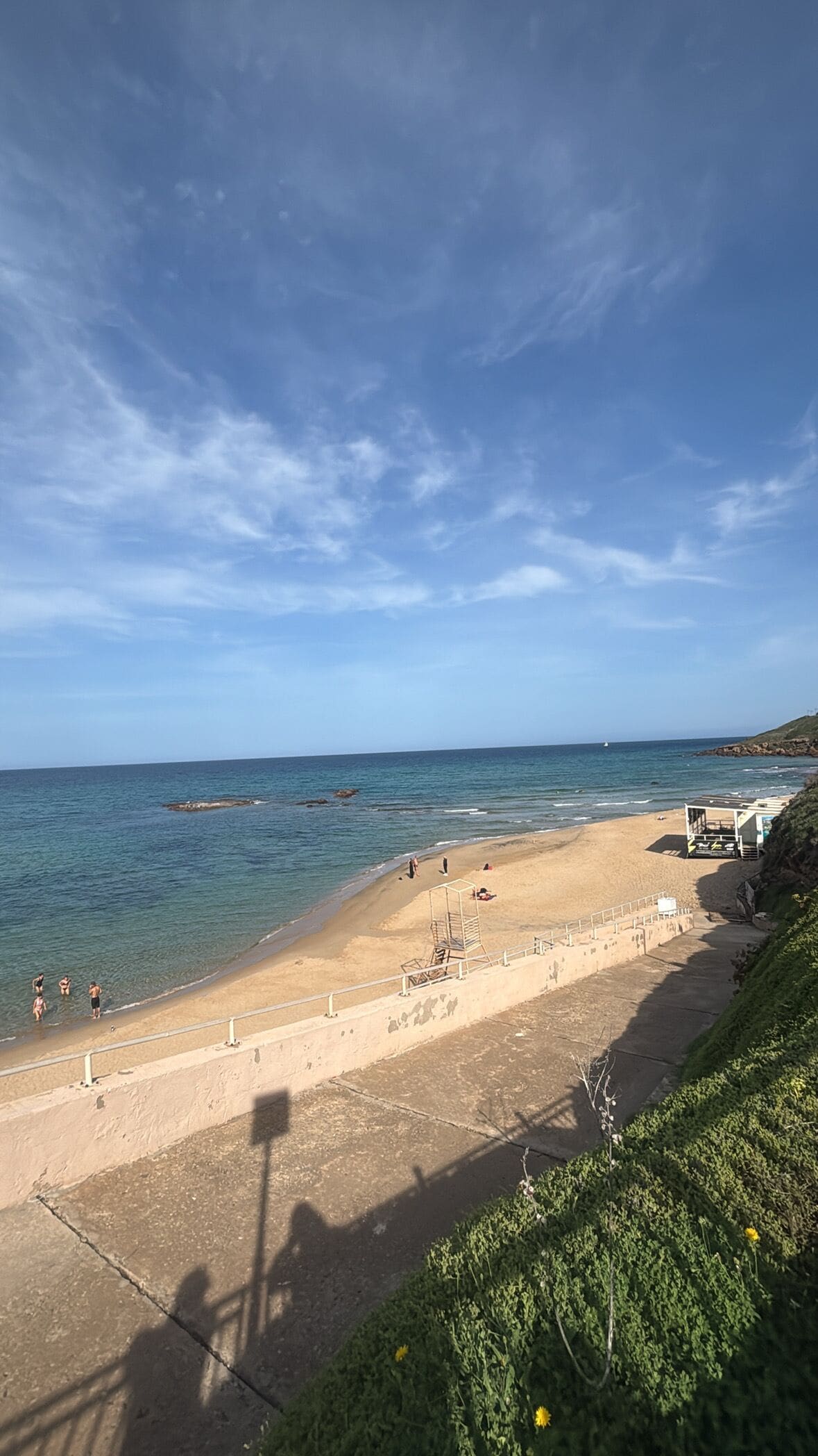 A beach with clear skies, calm water, and a lifeguard tower.