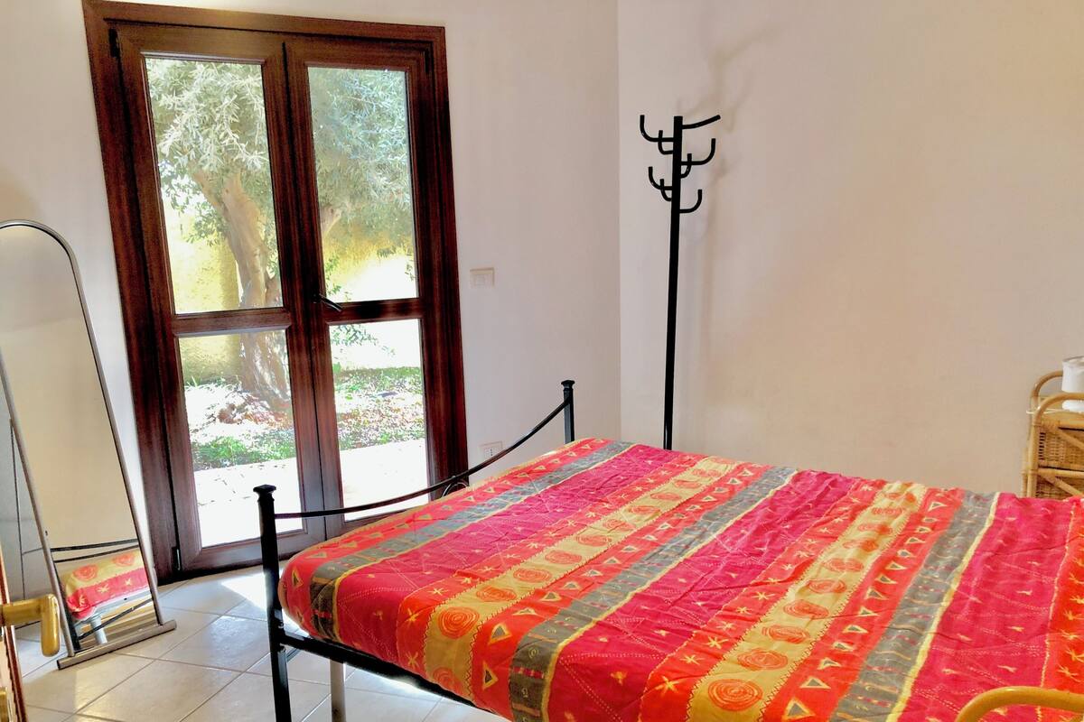 Ein Zimmer mit Bett, Fenster, Kleiderhaken und Tür.