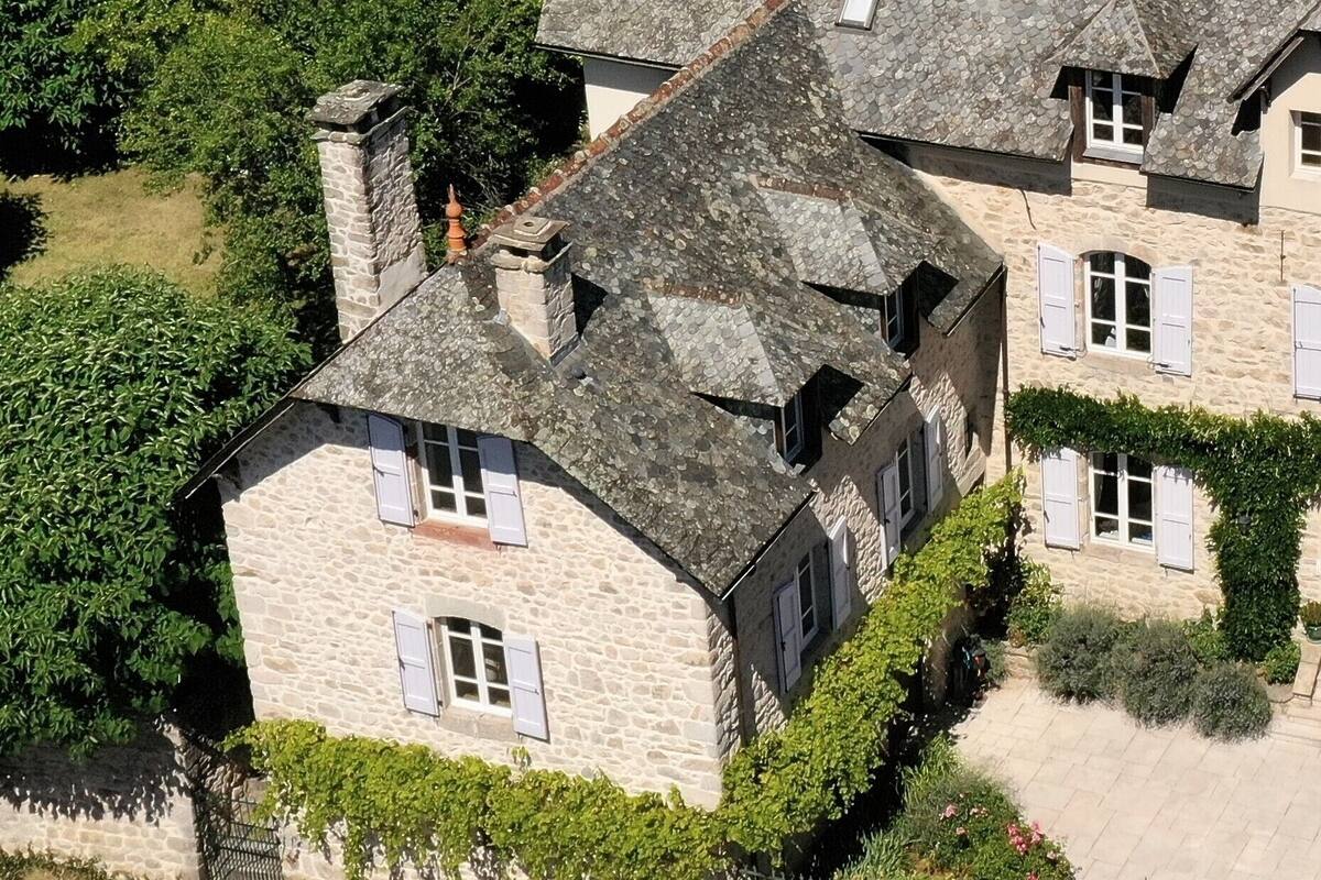 Un bâtiment en pierre doté de nombreuses cheminées, une petite fenêtre avec des volets et du lierre qui grimpe le long des murs.