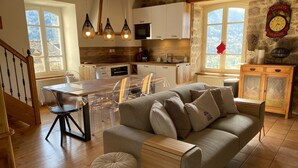 A cozy kitchen with a dining area, wooden flooring, and a stone wall. - Le Clos Saint Georges (Entraygues-sur-Truyere)