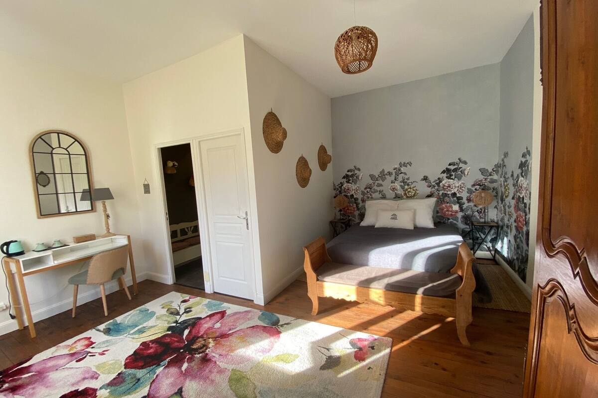 Une chambre à coucher avec un lit, un bureau et une chaise. Une porte donne accès à une autre pièce.