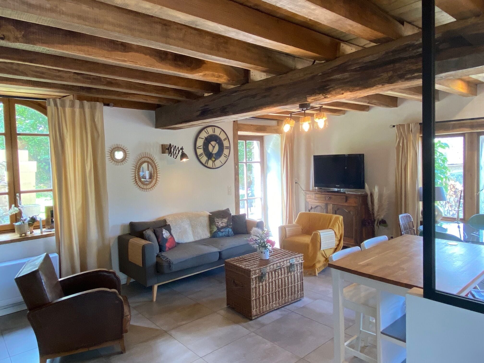 A living room with a sofa, a coffee table, a TV, and a dining area with a table and chairs.