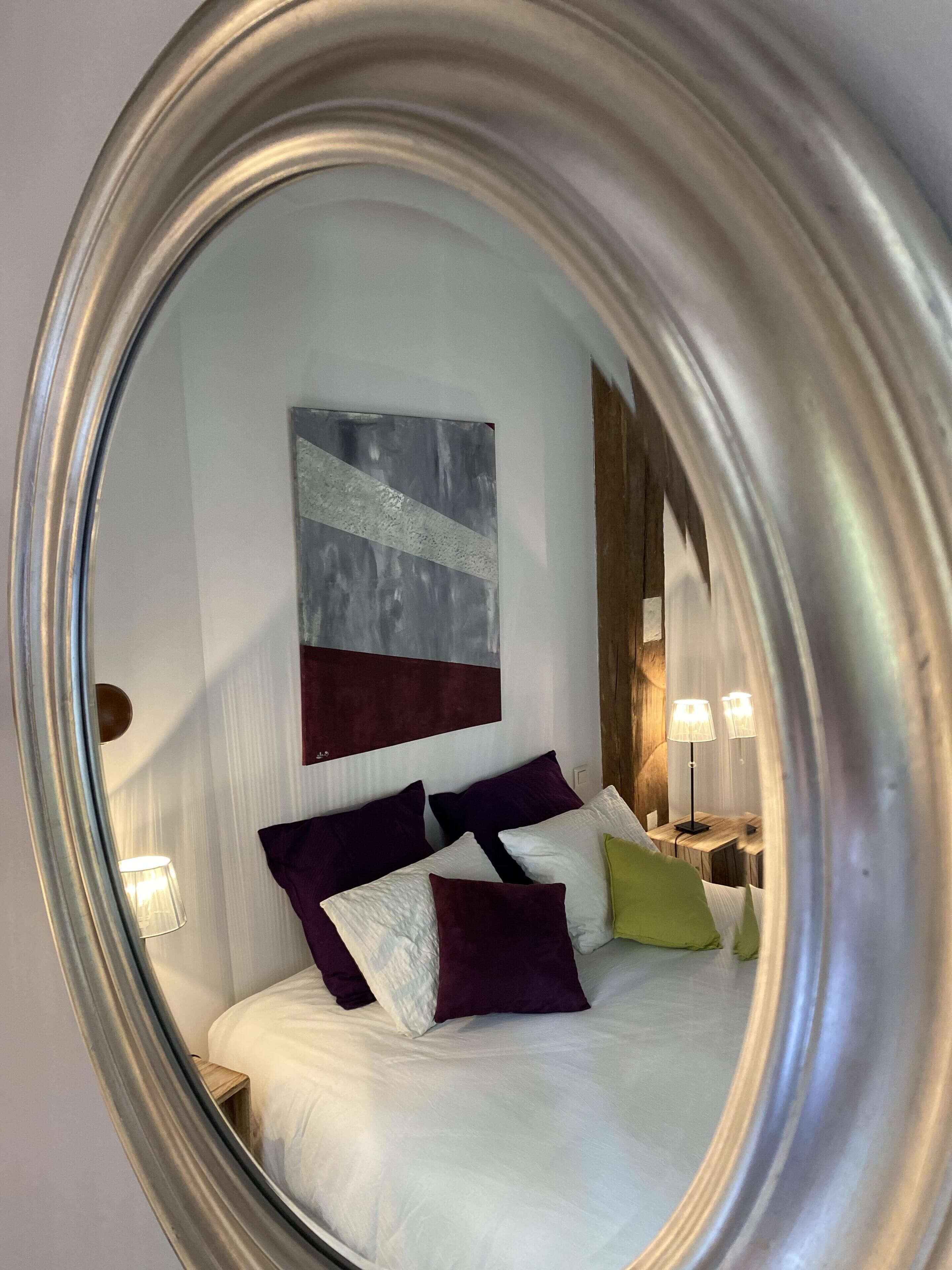 Una cama con varias almohadas, una obra de arte en la pared y lámparas de noche.