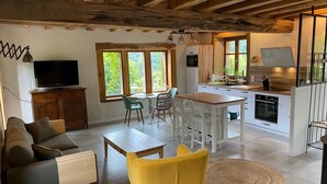 A modern kitchen with a dining area, wooden beams, and large windows. - Le Clos Saint Georges (Entraygues-sur-Truyere)