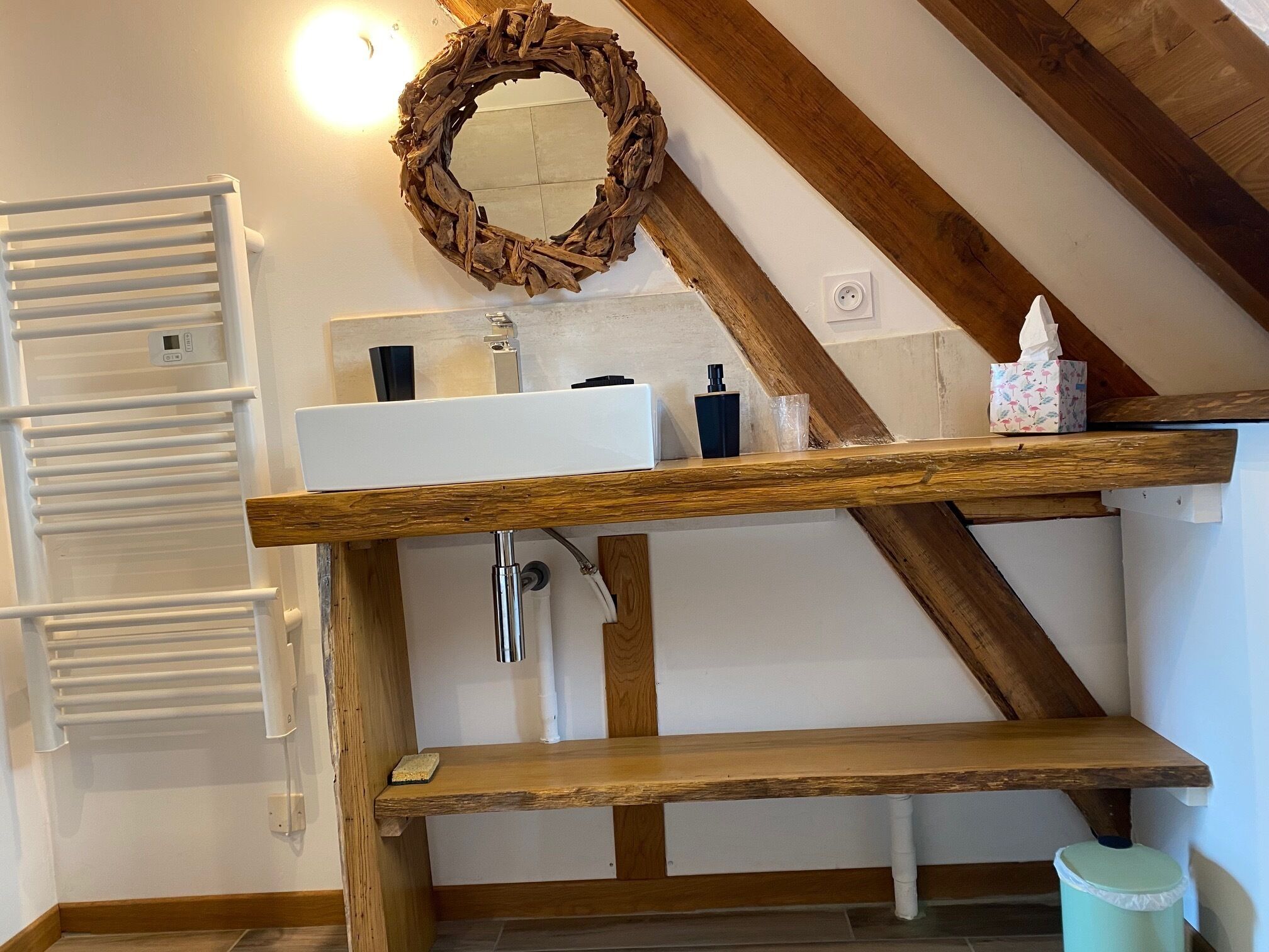 A bathroom with a wooden vanity, a white sink, a mirror, and a towel rack.