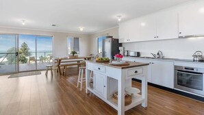 Una cucina moderna con mobili bianchi, un'isola in legno e vista sull'oceano.