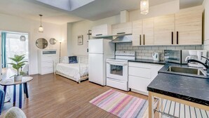 A modern kitchen with white cabinets, a black countertop, and a skylight. - St. Laurent Apt with Balcony & Skylight Near Parks (Montréal)