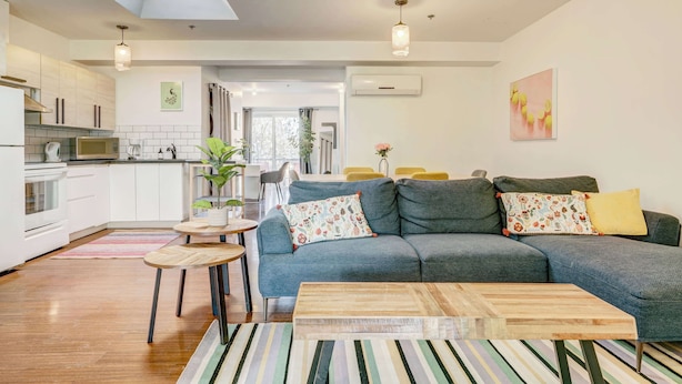A modern living room with a grey sofa, wooden coffee table, and striped rug. - St. Laurent Apt with Balcony & Skylight Near Parks (Montréal)