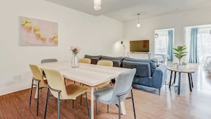 A modern living room with a dining table, sofas, and a TV. - St. Laurent Apt with Balcony & Skylight Near Parks (Montréal)