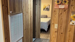 Un pasillo con paneles de madera, una cama con colcha estampada con flores y un cuadro colgado en la pared con girasoles.