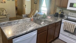 Una cocina con encimeras de granito, lavavajillas integrado, armarios de madera, microondas y estufa.