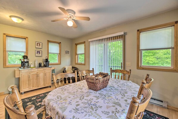 A dining area with a round table, wooden chairs, a ceiling fan, and a buffet cabinet.