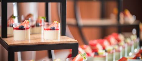 A dessert display with multiple glass servings on a wooden stand, each topped with a strawberry and a blueberry.