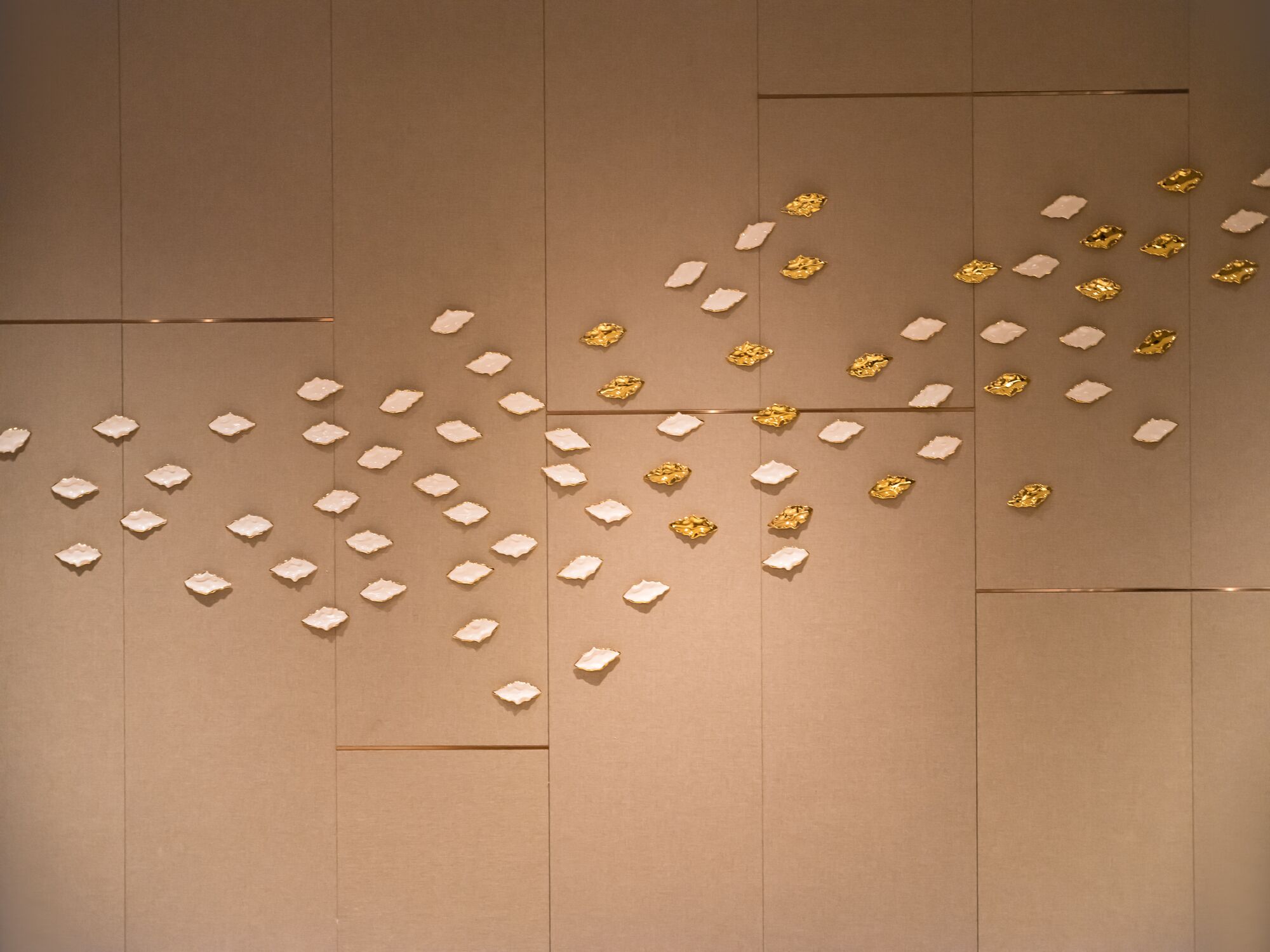 A wall with geometric patterns and scattered gold and white objects.