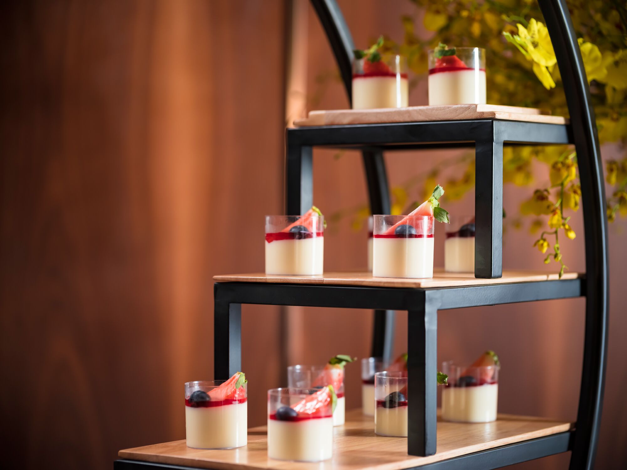 A dessert display on a black metal stand with multiple tiers.