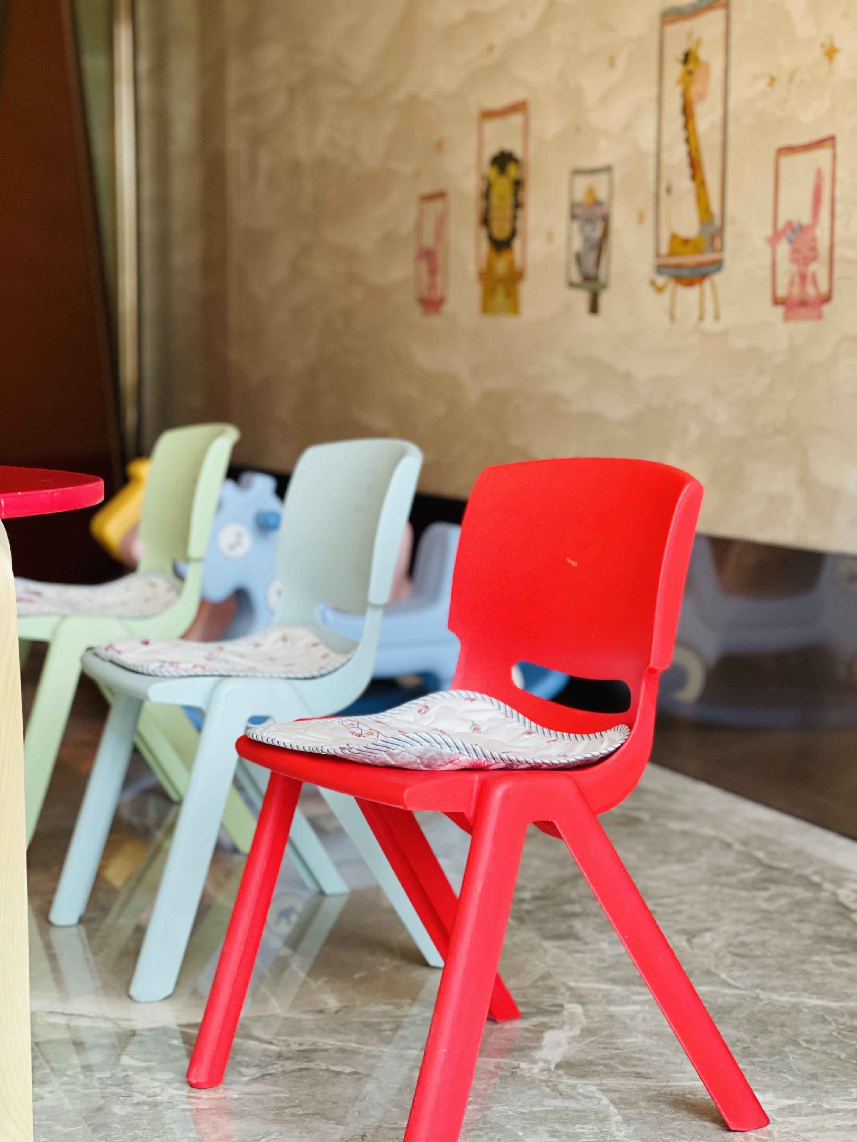 Een rij kleurrijke plastic stoelen met gevlochten zitting en rugleuning, opgesteld op een betegelde vloer.