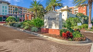 En hotelindgang med et skilt, der viser "Azure 1150", omgivet af anlagte haver og palmer.