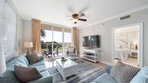 En moderne stue med sofa, sofabord og fjernsyn. Der er en balkon med stol og bord.