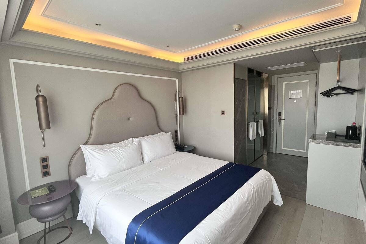 A hotel room with a bed, bedside table, and a bathroom with a shower and toilet.