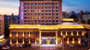 Un hotel de varios pisos con una entrada llamativa y un cartel grande.