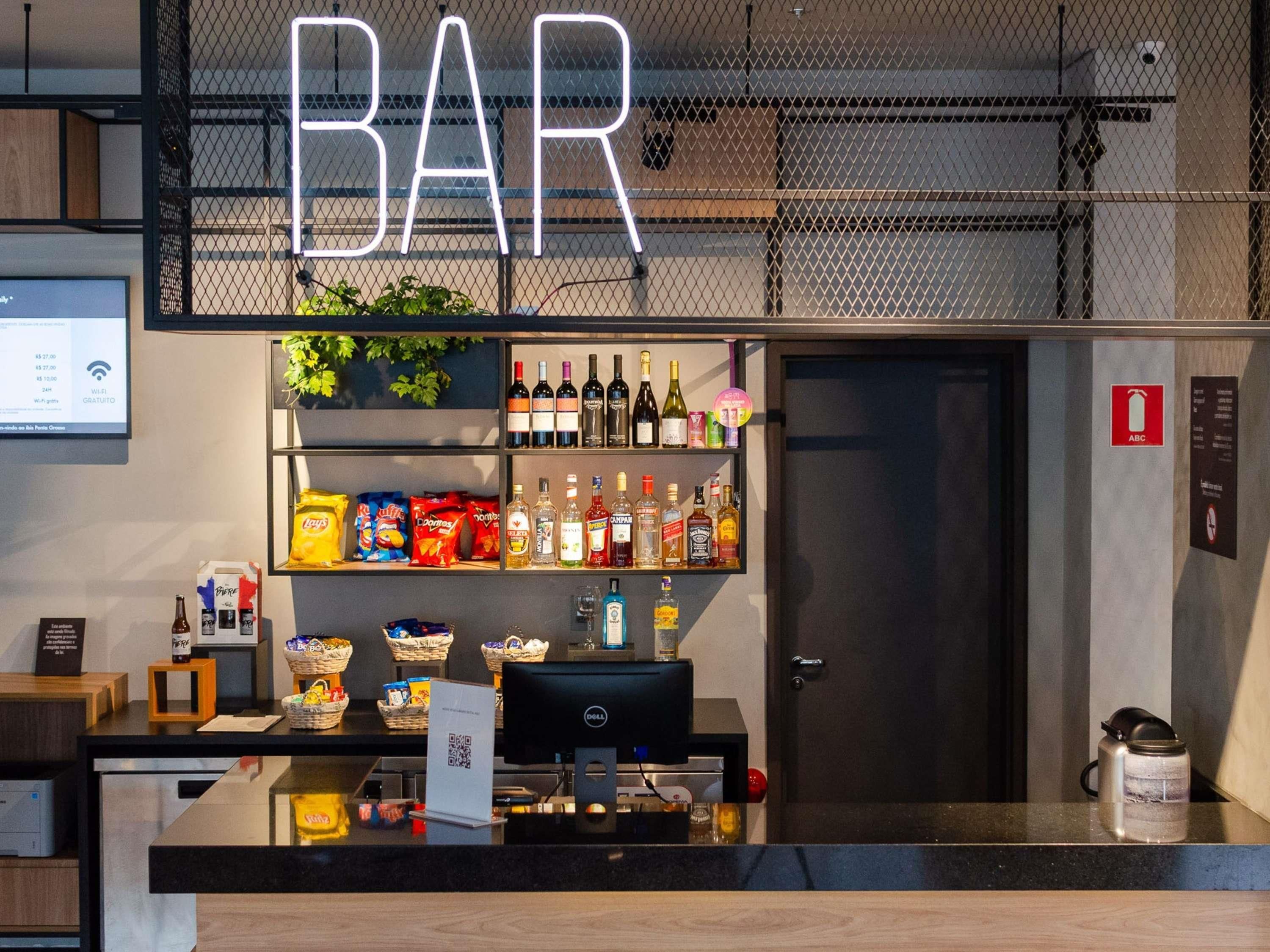 Un espace bar avec un panneau indicateur, des étagères remplies de collations et un écran d’ordinateur.