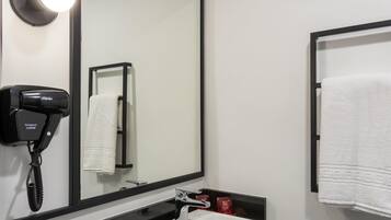Un baño con un espejo grande, un secador de pelo, un lavamanos y un toallero.