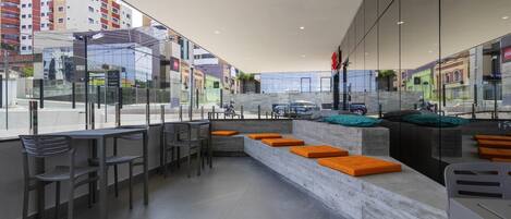 A modern interior with a seating area, a counter, and large windows offering a view of the street.