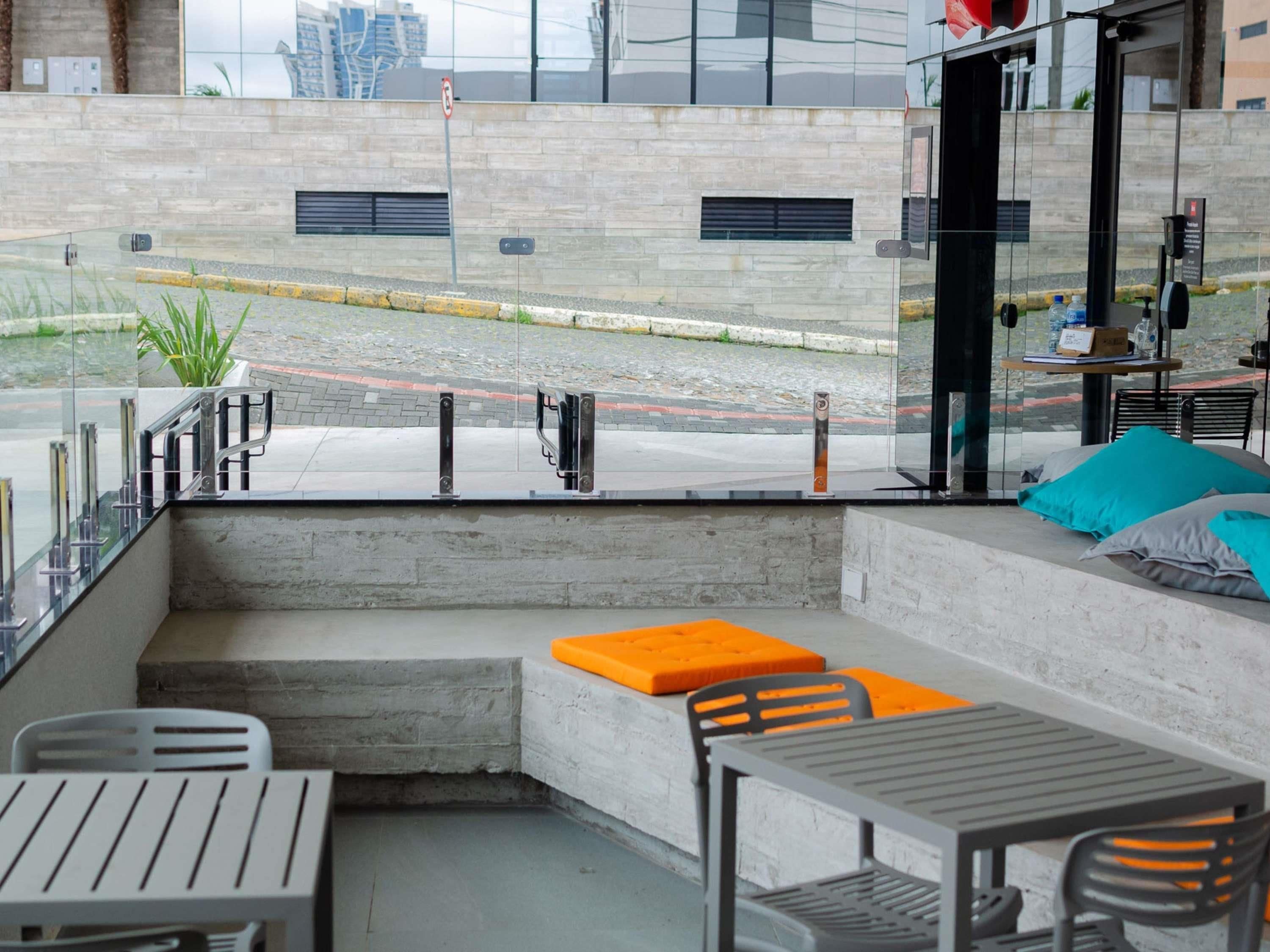 A modern outdoor seating area with concrete steps, metal railings, and orange cushions.