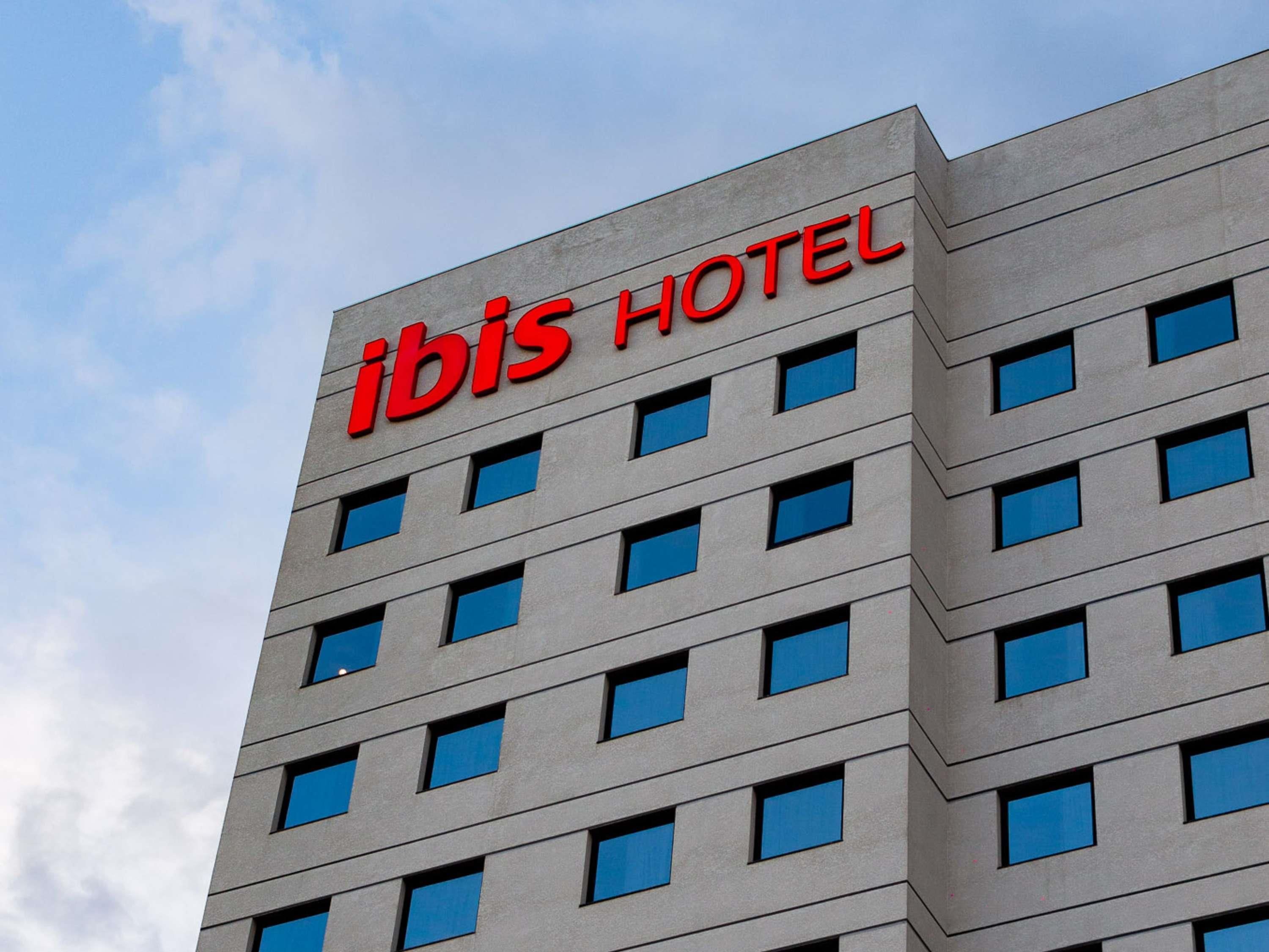 Un edificio de hotel con un letrero que dice 'ibis HOTEL' en letras rojas.