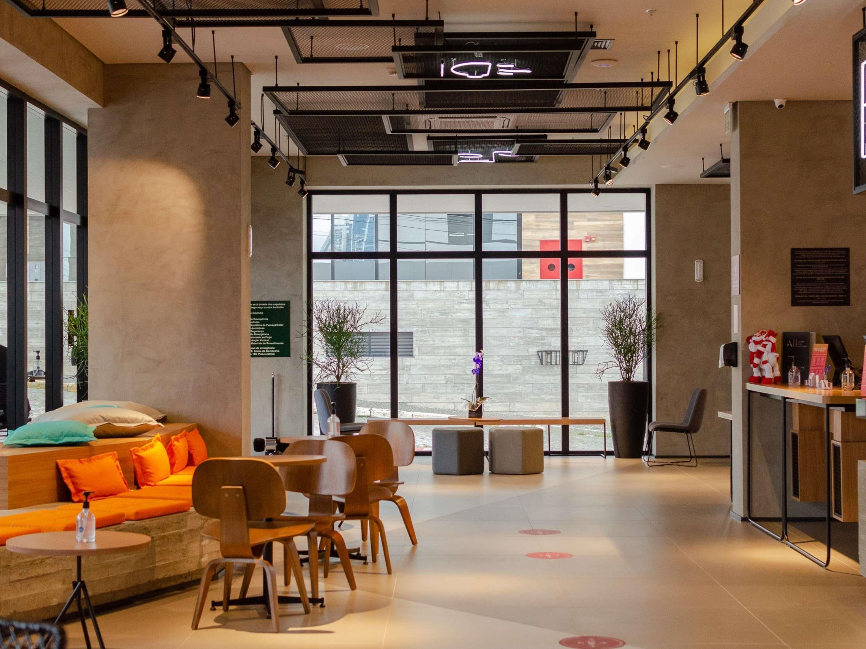 Un intérieur moderne comprenant un espace salon, un comptoir d’accueil et de grandes fenêtres.