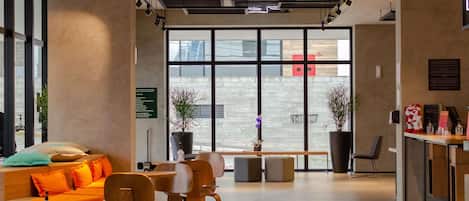 A modern interior with a seating area, a reception desk, and large windows.