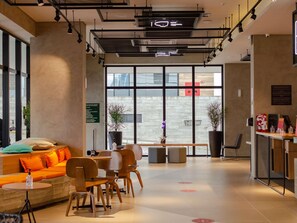 A modern interior with a seating area, a reception desk, and large windows. - Ibis Ponta Grossa (Ponta Grossa)