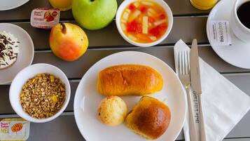 A breakfast setting with a plate of pastries, a bowl of fruit, and a glass of orange juice.