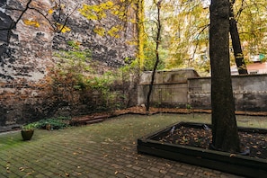 Relax in a serene courtyard surrounded by lush greenery and a rustic brick wall.