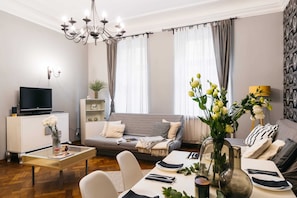 Relax in this stylish living room with a comfortable sofa, flat-screen TV, and dining area.