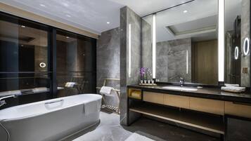 A modern bathroom with a freestanding bathtub, a large mirror, and marble flooring.
