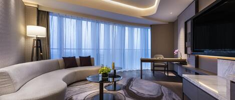 A modern living room with a curved sofa, a round coffee table, and a TV mounted on the wall.