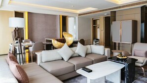 Una habitación de hotel moderna con sofá, mesa de centro, escritorio y armario.