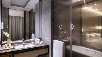 A modern bathroom with a large mirror, two sinks, a shower area, and a towel rack.