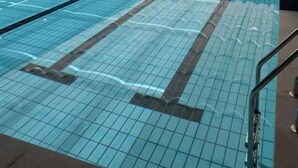 En indendørs swimmingpool med tydelige baneafmærkninger, flisegulv og et loft med bølgemønster.