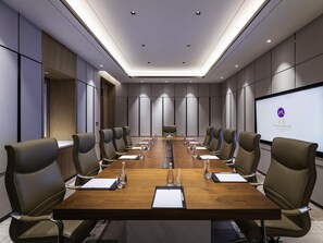 A conference room with a long table, multiple chairs, and a presentation screen.