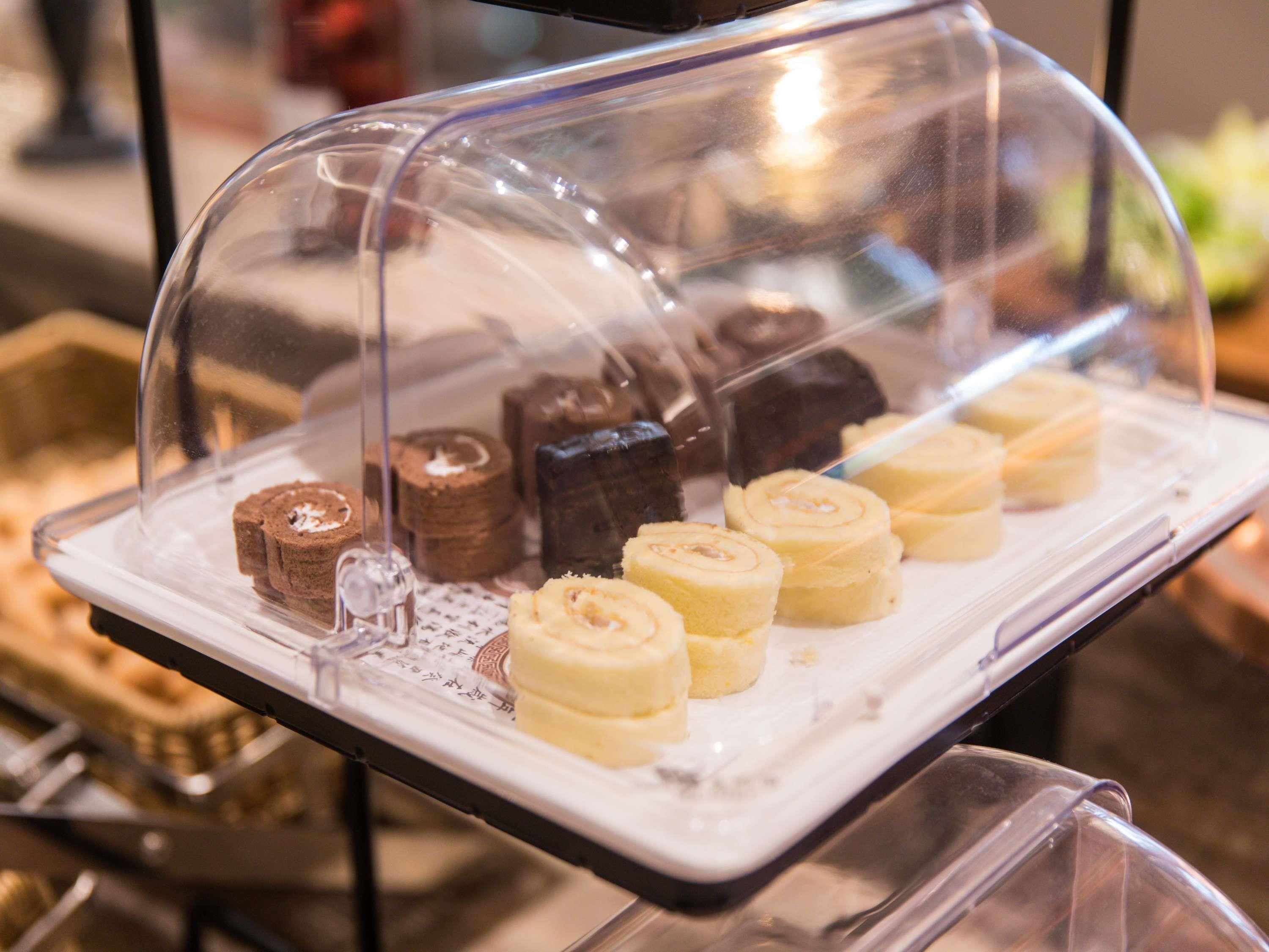 Une vitrine contenant diverses pâtisseries, protégées par un couvercle en verre.