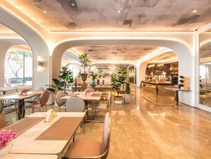 Een ruime hotel lobby met een centrale bar, meerdere zithoeken en grote ramen voor natuurlijk lichtinval.