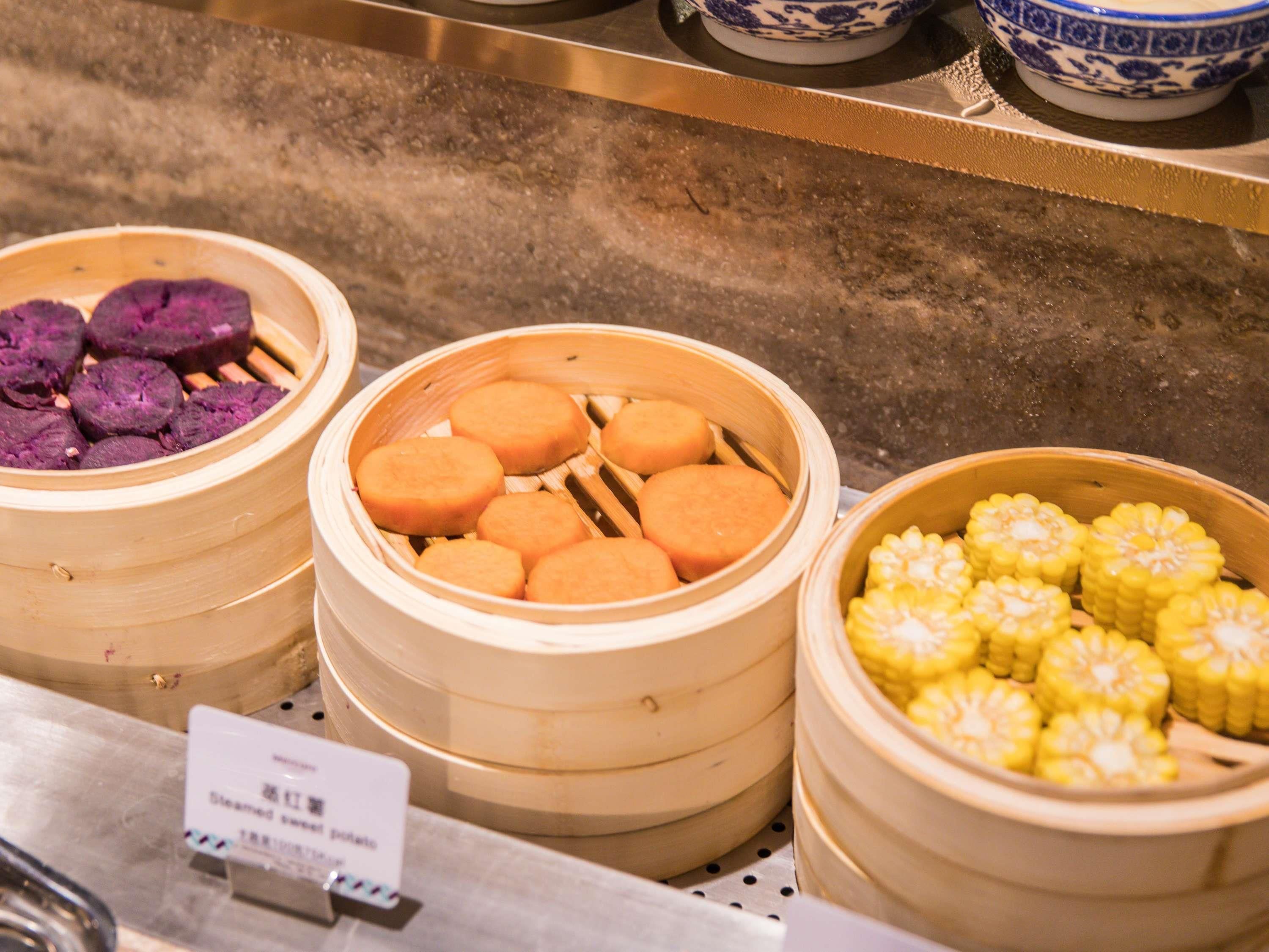 A food display with various steamed items in bamboo baskets.