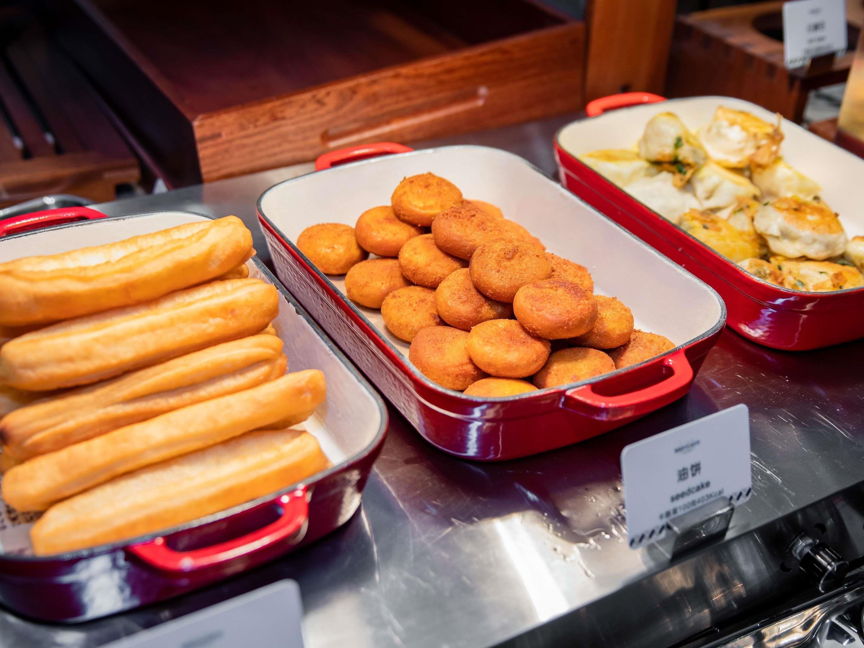 A buffet with trays of food including breadsticks, fried balls, and dumplings.