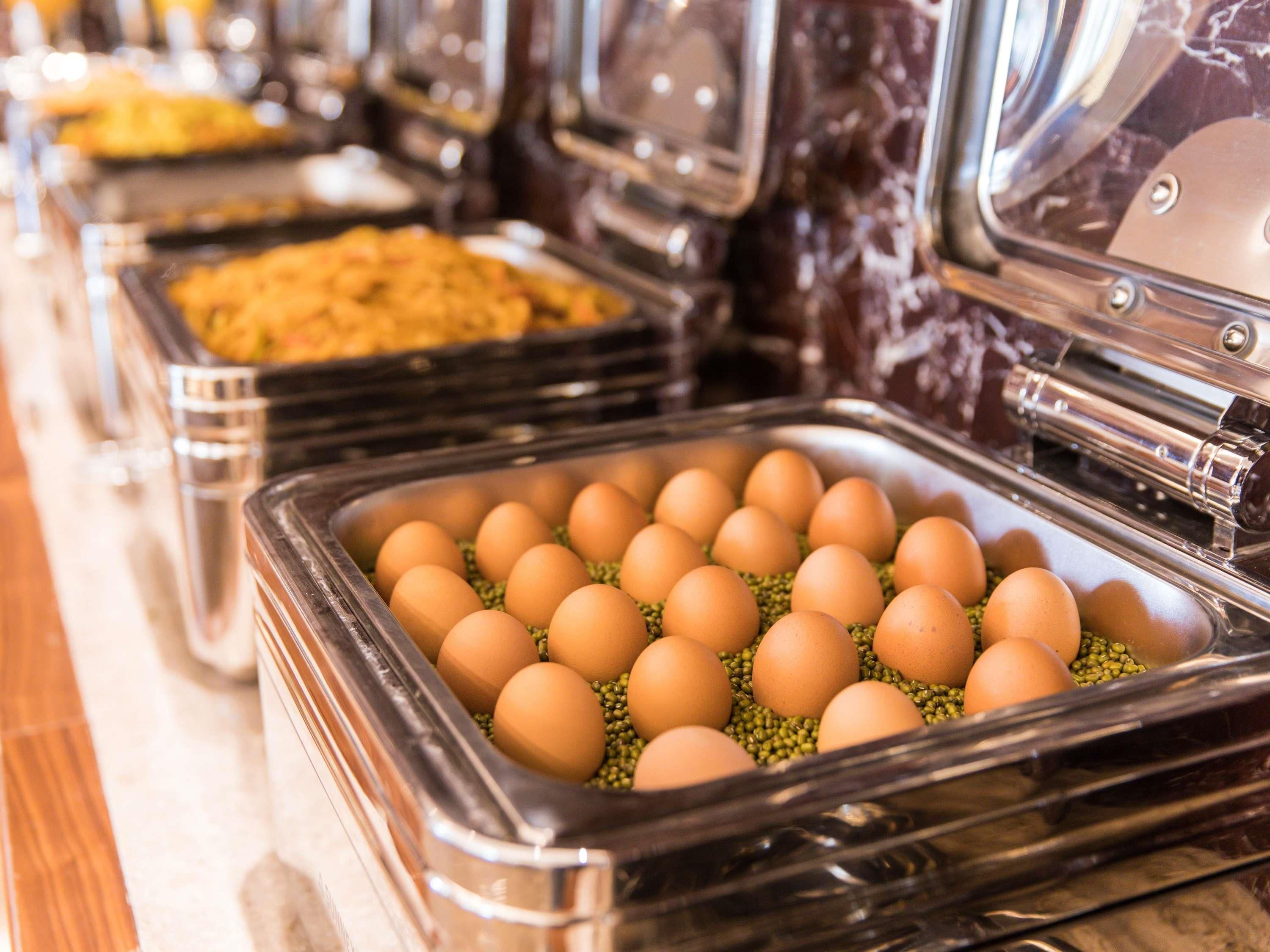 A buffet with various food items, including a tray of eggs on a bed of green peas.