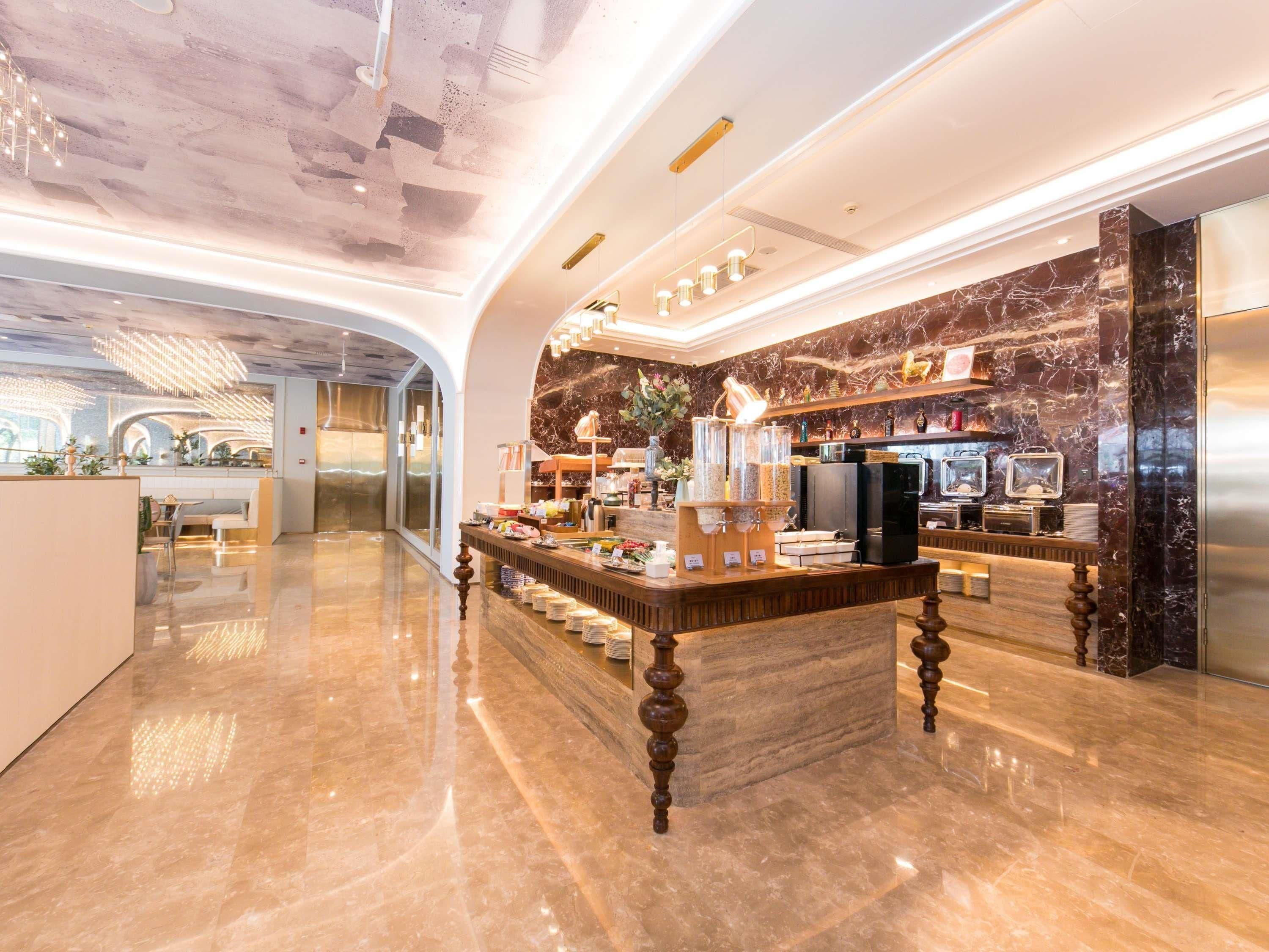 Un moderno vestíbulo de hotel con una recepción de mármol, una barra de café y una zona de estar con vistas a la ciudad.