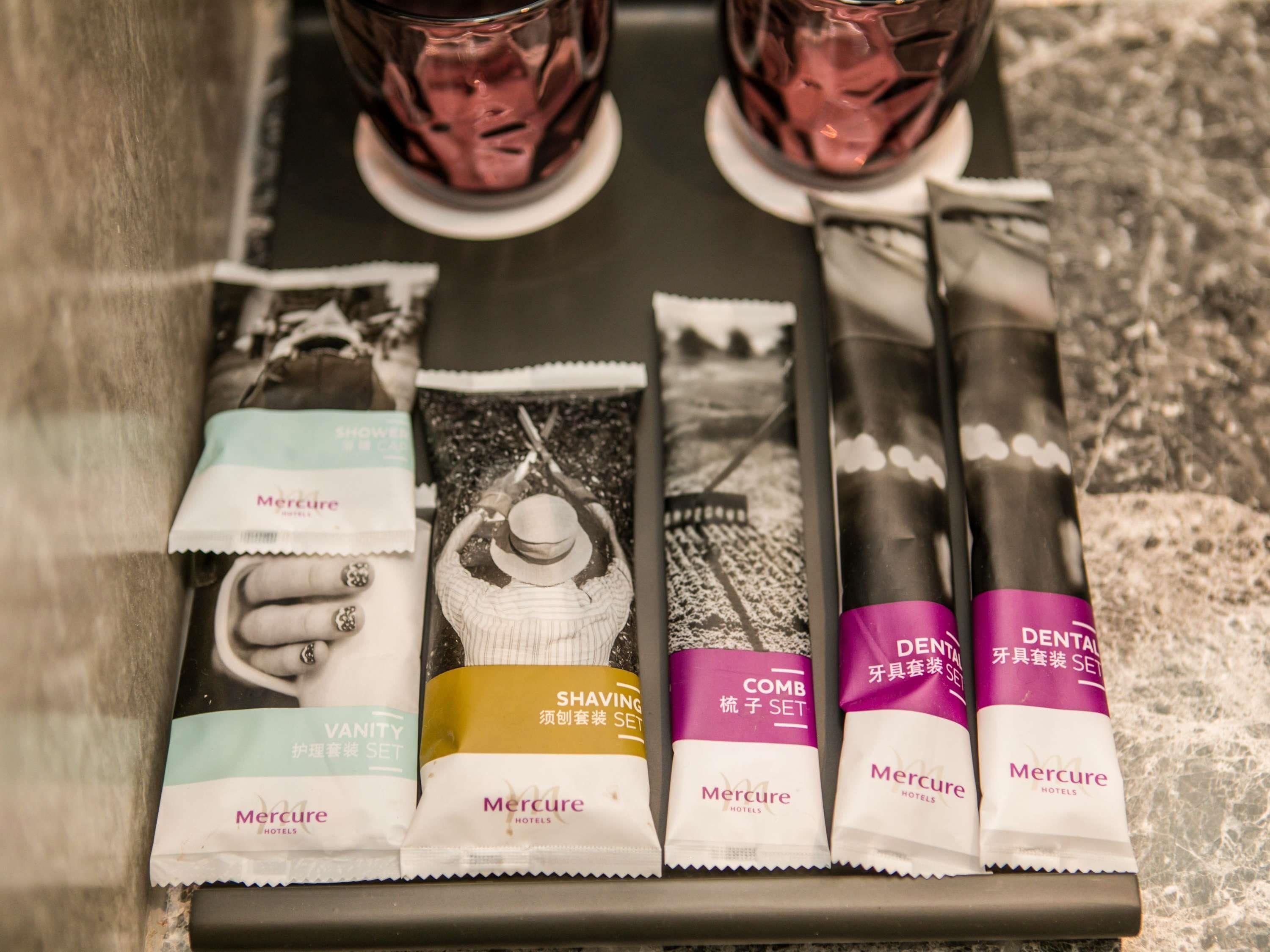 Bandeja con diversos artículos de aseo personal, incluyendo un kit de afeitar, peine y productos para el cuidado dental, junto con dos vasos de agua.