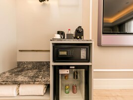 A compact kitchenette with a microwave, kettle, and a small refrigerator containing beverages.