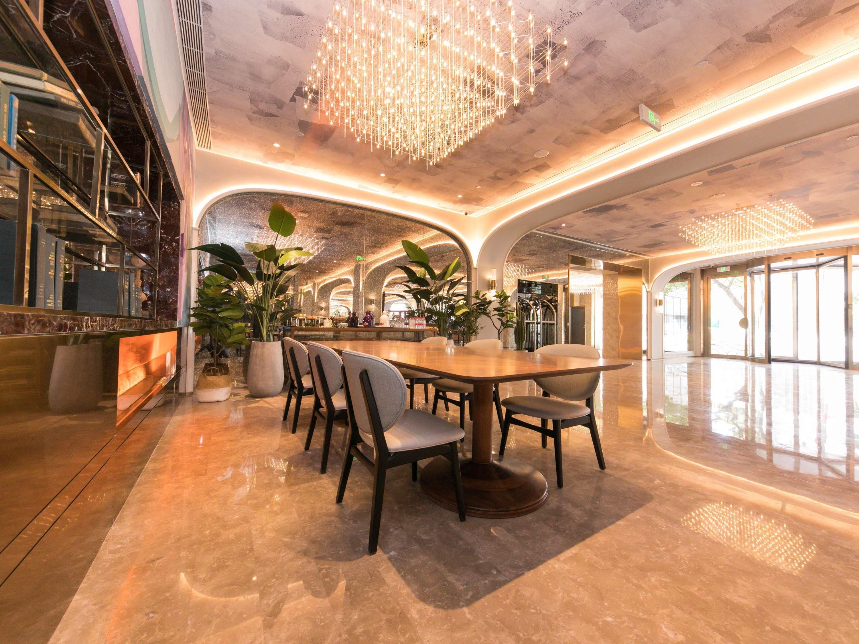 Un intérieur spacieux et moderne, doté d’un coin repas central, de grandes fenêtres et d’un éclairage décoratif.